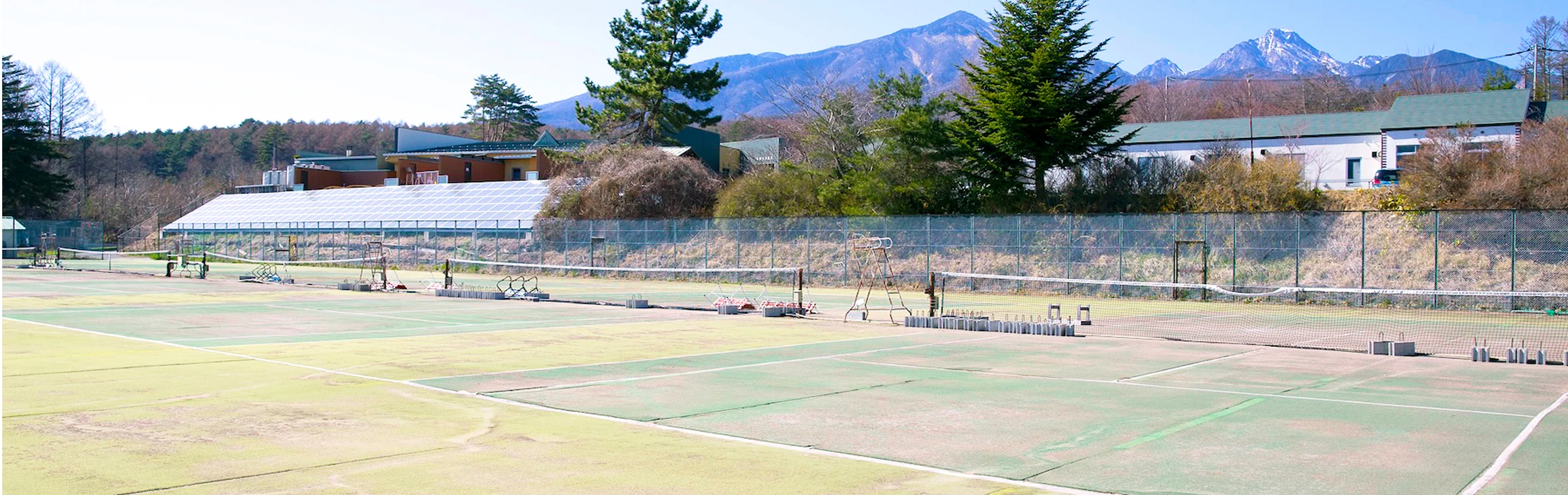 八ヶ岳を背景にした、かつてのテニスコートを活用したパノラマ温泉オートキャンプ場の全景