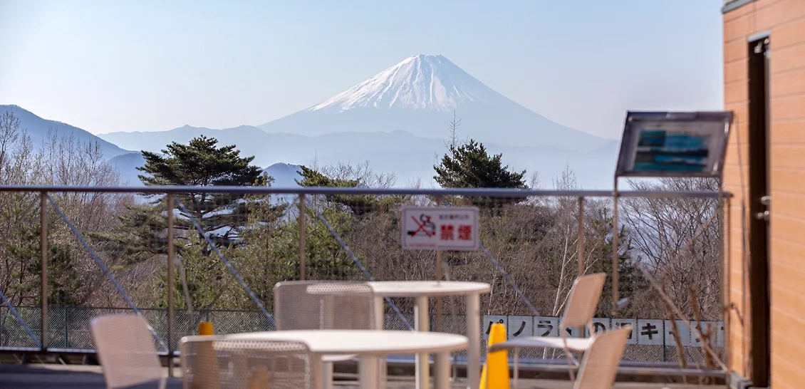 屋外のテラスに白いテーブルとイスが設置され、富士山と南アルプスの絶景が望める開放的なスペース
