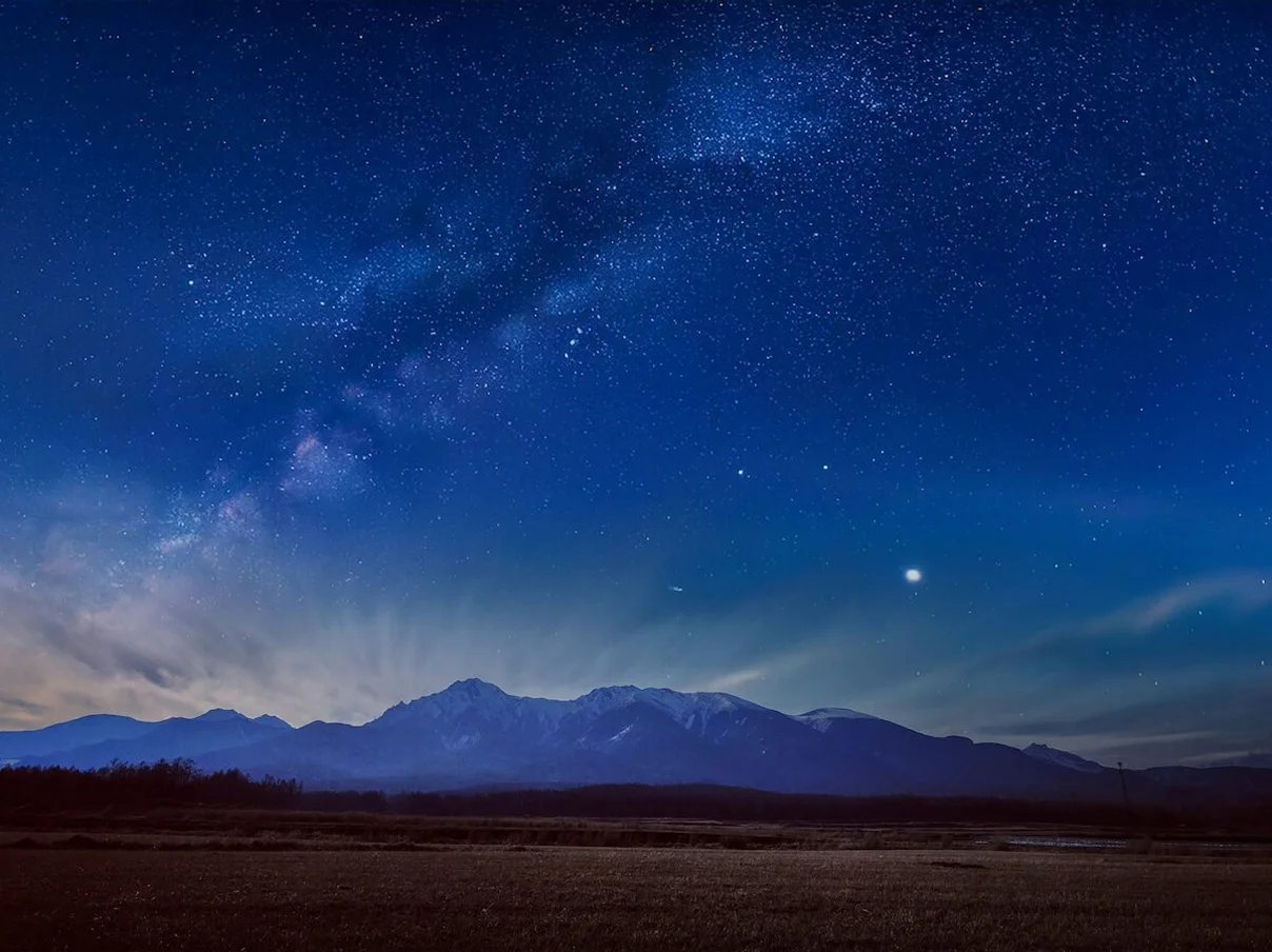 夜空に広がる天の川と山々の星景