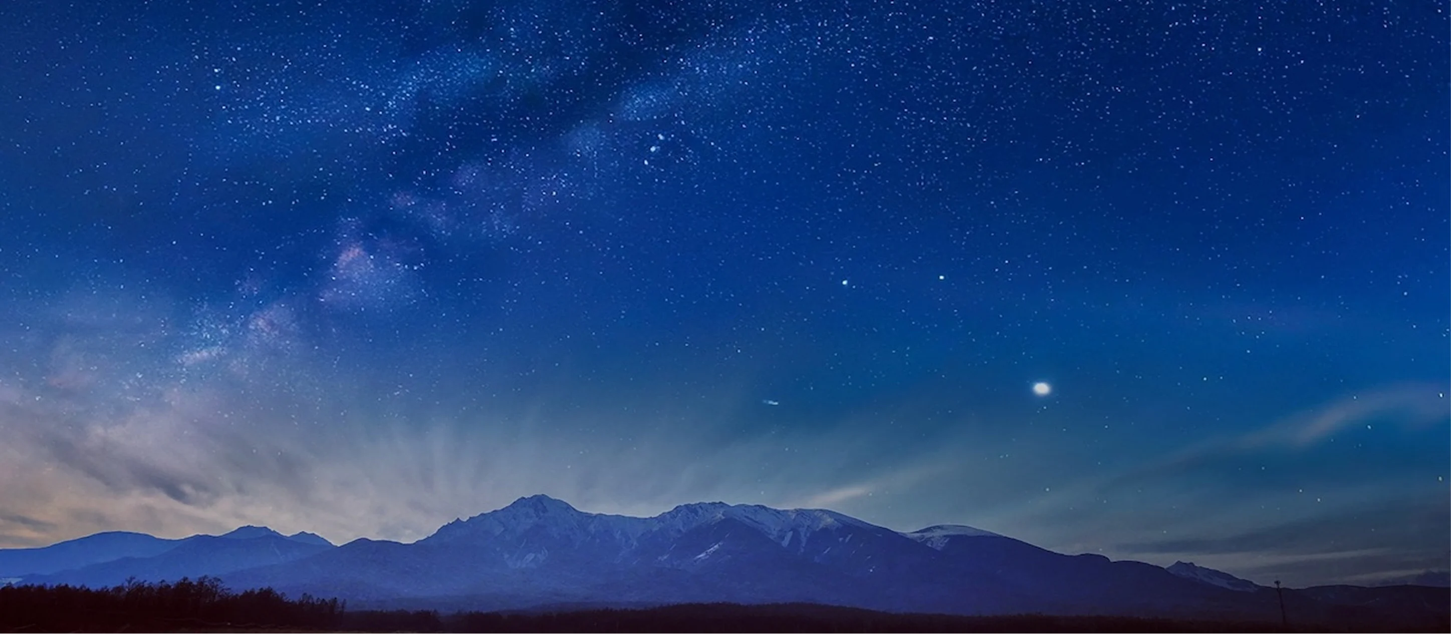 夜空に天の川がかかる星空と山々のパノラマ風景